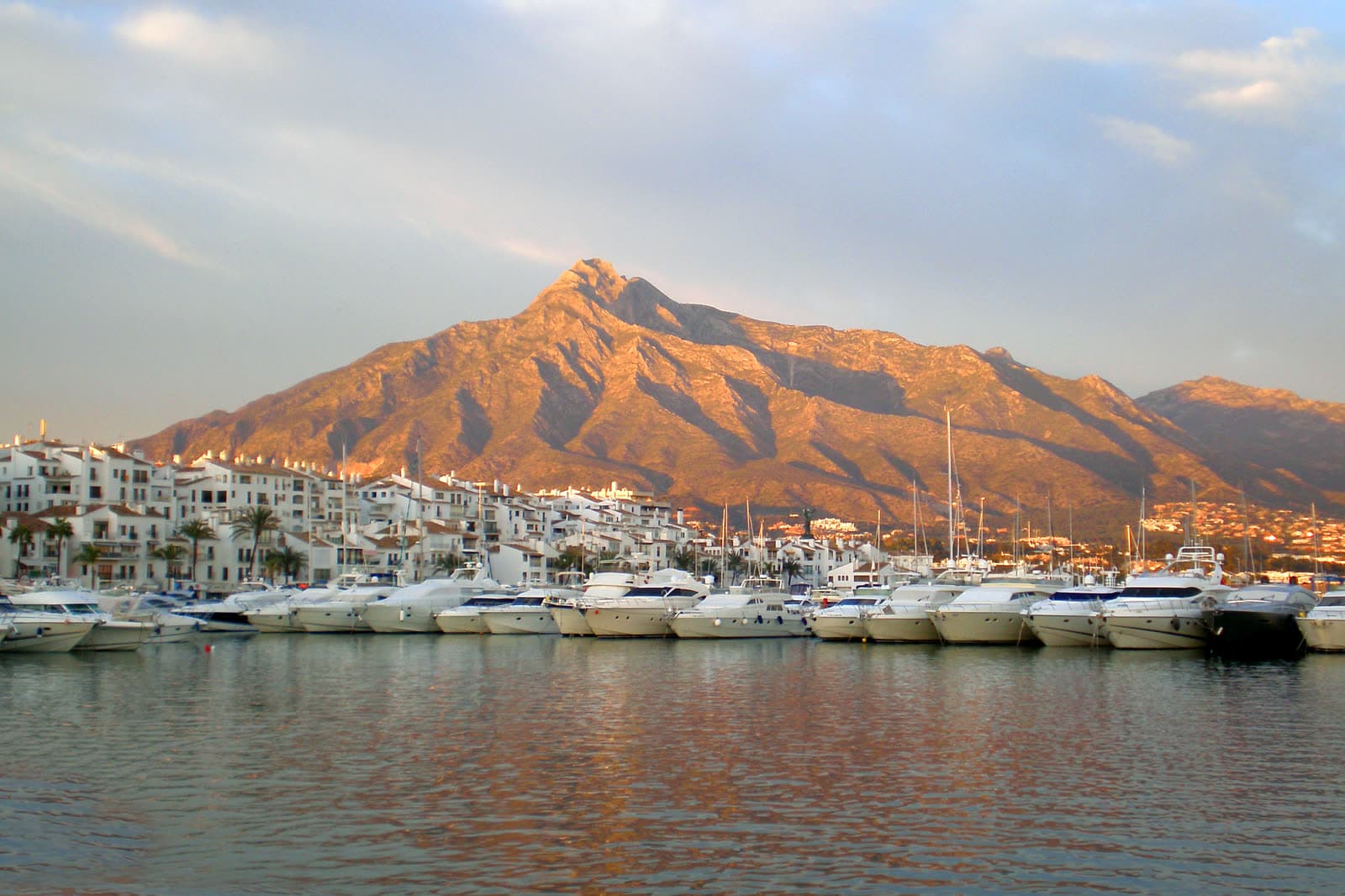 Yachts moored in the Puerto Banús marina with La Concha mountain glowing in the evening light