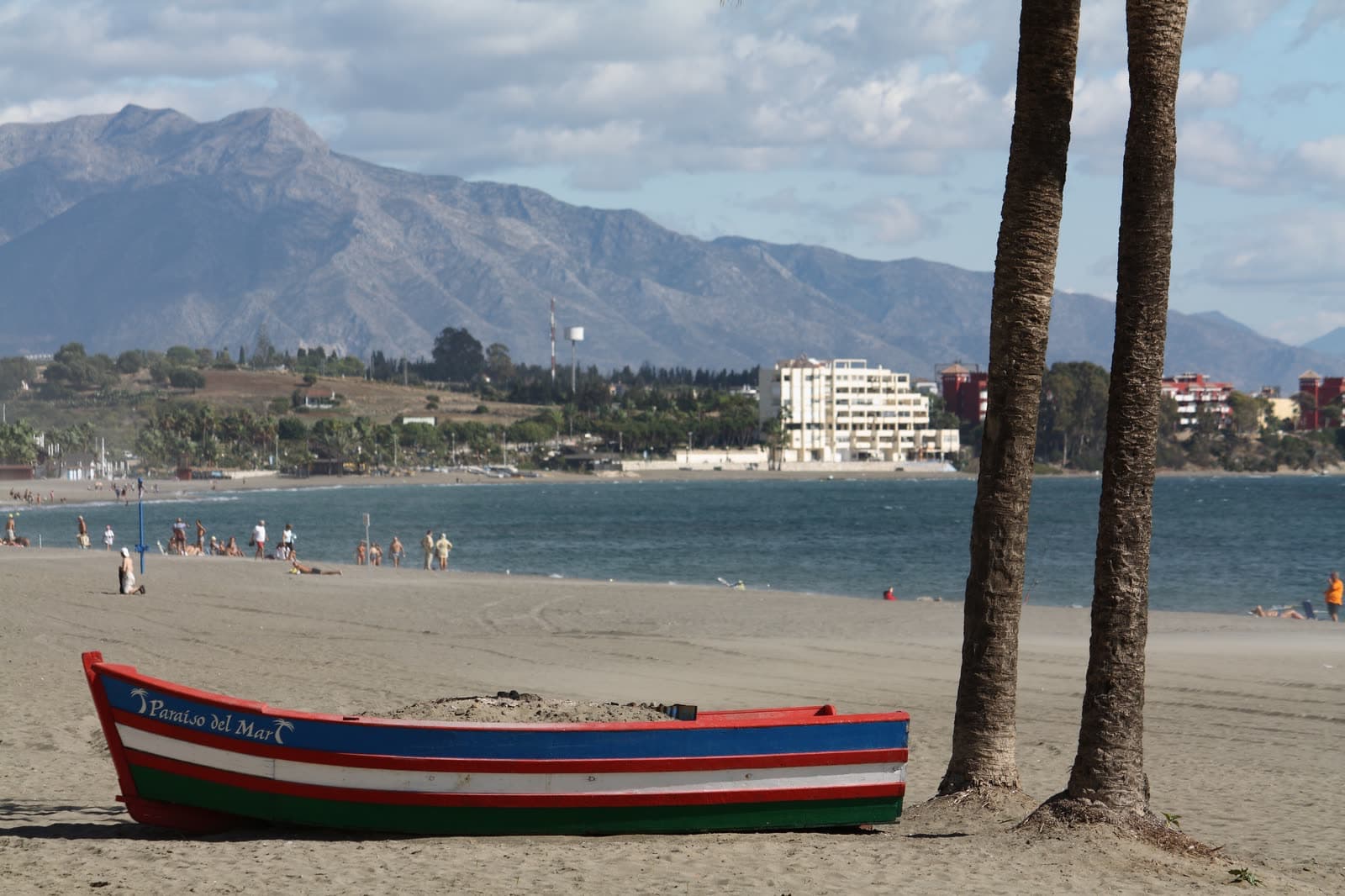 A painted fishing boat on Estepona beach, looking along the coast towards La Concha mountain above Marbella