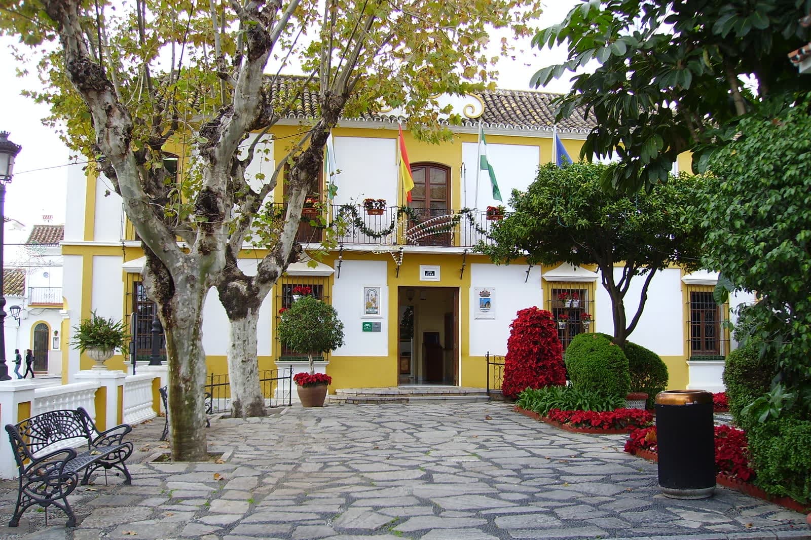 Estepona town hall, a yellow and white building with flags on a paved square